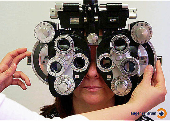 Der Patient blickt durch Öffnungen des Phoropters, vor die jeweils eine Prüflinse geschoben wird.